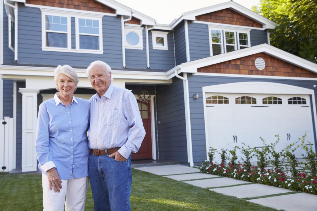 Senior Couple Standing Outside House