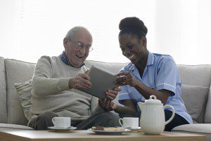 Home caregiver and elderly man laughing together