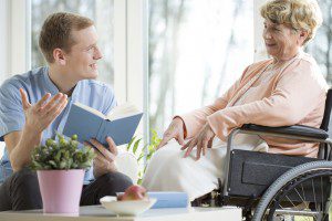 Caregiver reading to senior woman at home