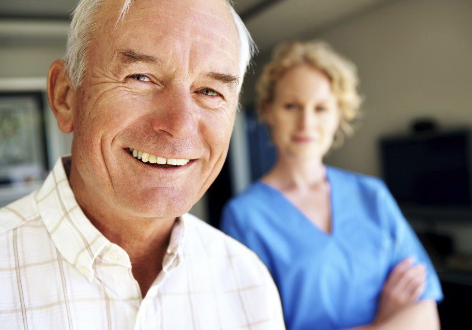 Closeup portrait of an elderly man with a young nurse in the background - Copyspace