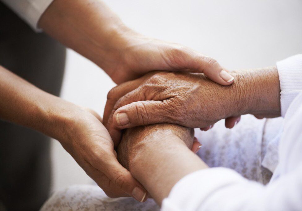 Close up of a young caucasian woman's hands holding a senior ethnic woman's hands