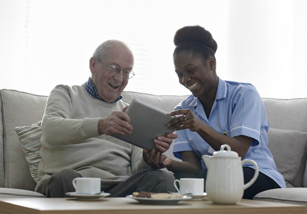 Home caregiver and elderly man laughing together